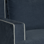 Close-up of a dark blue upholstered chair with a visible stitching detail.