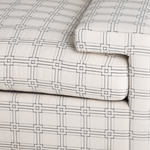Cream fabric sofa upholstery with black geometric grid pattern and plush cushioning.