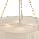 Close-up of a hanging chandelier with a large circular white fabric shade, gold chain suspension, and a central vertical rod against a white background.