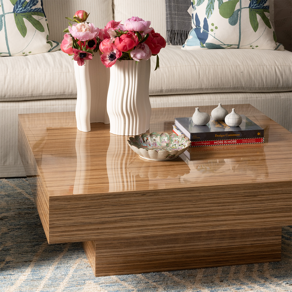 Rectangular wooden cocktail table with natural wood grain, featuring a stepped base and decorated with two white ceramic.