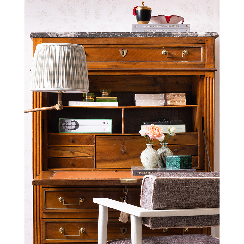 A styled home decor scene featuring two marbled ceramic vases with flowers, set against a wooden dresser background with books.