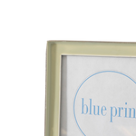 Close-up of a light green picture frame corner with a white print inside featuring blue text and a blue circle outline.