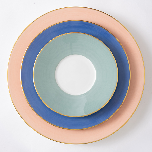 Stack of ceramic plates with concentric circles in pink, blue, and green on a white background