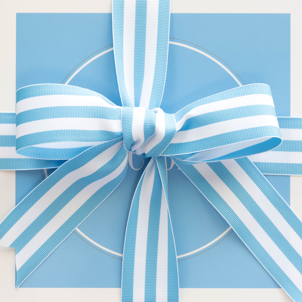 Light blue gift box with white circular detail, topped with a wide blue and white striped satin ribbon bow.