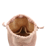A close-up of a woven drawstring bag opening, showing a peach-pink exterior patterned with small blue and black motifs, and a tan-orange patterned lining.