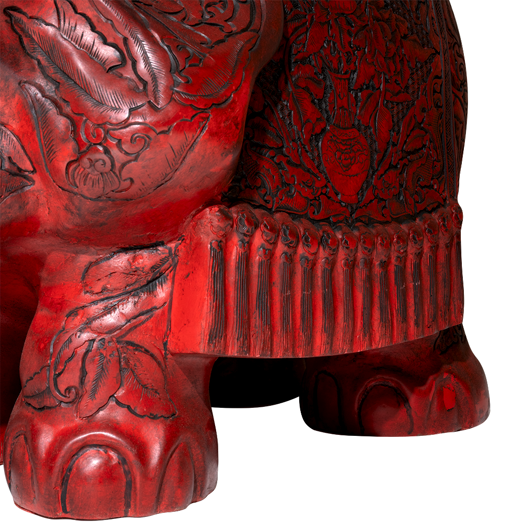 Close-up of a red carved elephant with intricate patterns on a white background