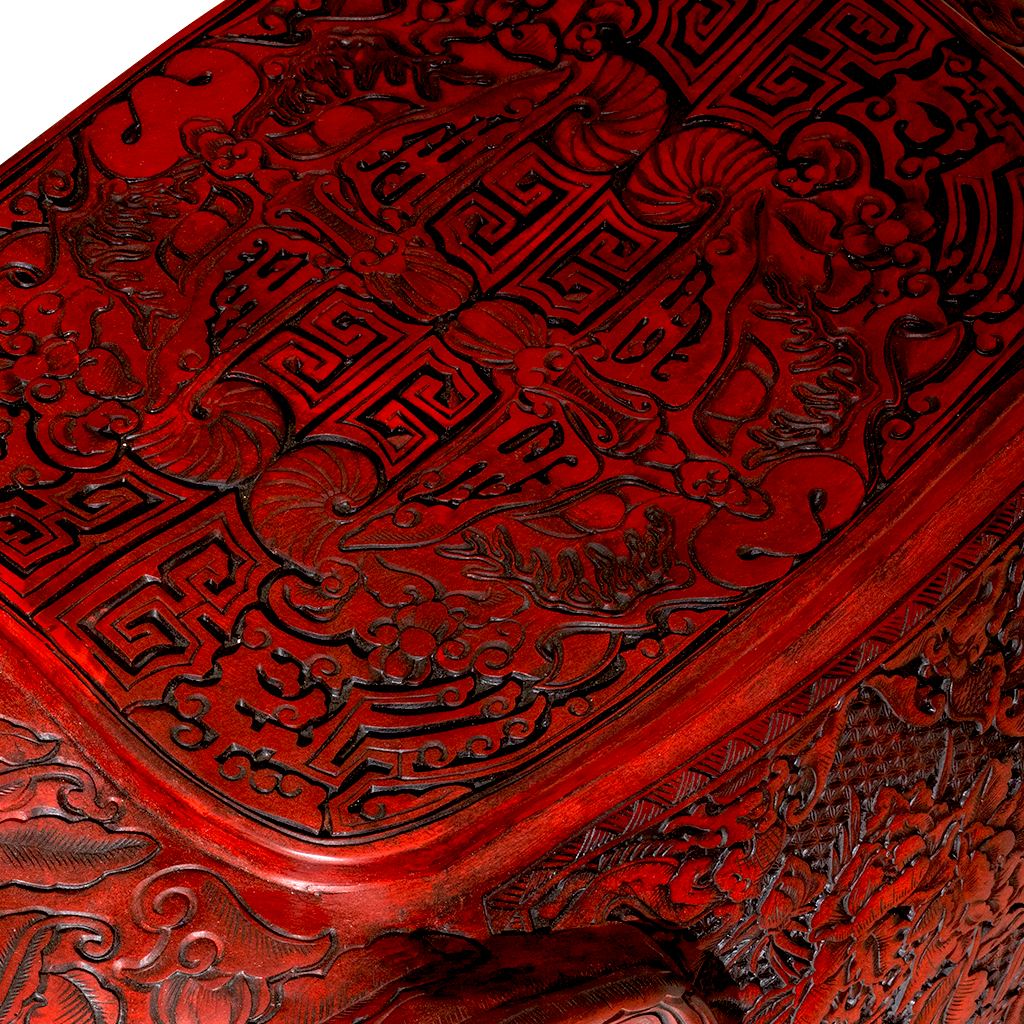 Close-up of a red wooden box with intricate carvings on a white background