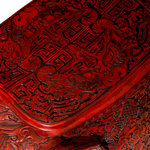 Close-up of a red wooden box with intricate carvings on a white background