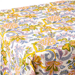 A close-up of a tablecloth with a vibrant, multicolored floral and paisley block print on a white base. The pattern features prominent yellow, pink, blue, and green motifs.