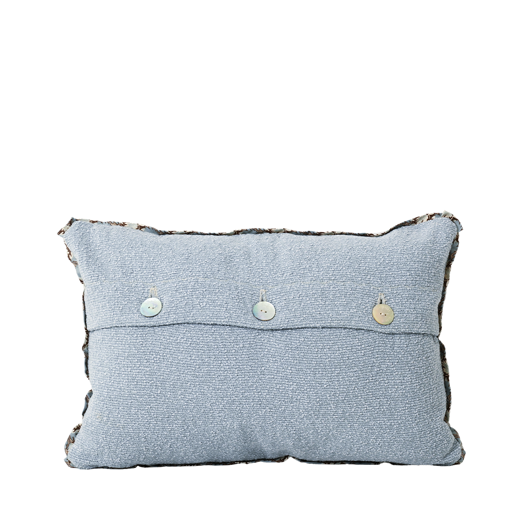 Light blue pillow with decorative buttons on a white background