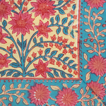 Colorful tablecloth with red floral patterns and blue leafy accents on cream and turquoise background.