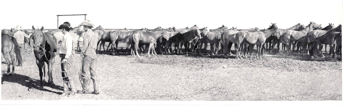 Two men with a group of horses in a line, likely in a ranch setting.