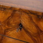 Close-up of a polished wooden side. table with a rich warm brown grain pattern, a central black diamond-shaped inlay holding a silver key, and thin dark inlaid lines.