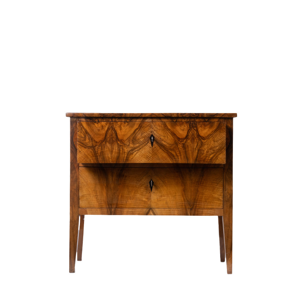 A vintage wooden nightstand with two drawers featuring intricate marquise-shaped wood grain patterns, small dark metal pulls, and tapered legs, shown against a plain white background.