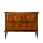 Front view of an antique Biedermeier two-drawer chest featuring striking bookmatched walnut veneer with richly figured wood grain across the drawer fronts. Simple round pulls, tapered legs, and clean, balanced proportions emphasize the piece's refined craftsmanship and elegant design.