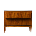 Front view of an antique Biedermeier two-drawer chest showcasing dramatic bookmatched walnut veneer with richly figured wood grain across the drawer fronts. The chest features simple round pulls, tapered legs, and clean, elegant lines that emphasize its refined craftsmanship.