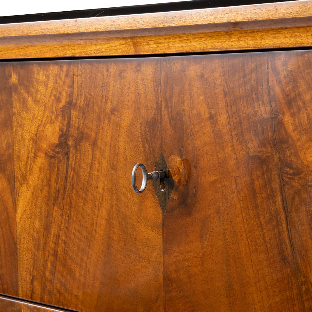 Close-up of a polished wood cabinet door with a warm brown grain pattern and a small metal keyhole lock.