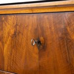 Close-up of a polished wood cabinet door with a warm brown grain pattern and a small metal keyhole lock.