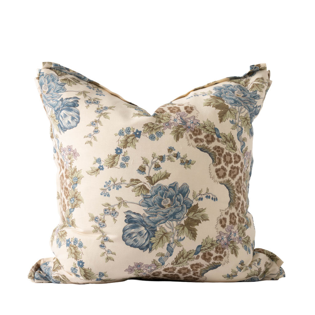 Decorative square pillow featuring an elegant botanical print with large blue flowers, delicate floral sprigs, and olive green foliage against a warm ivory background. Soft lavender accents and winding brown branches add depth to the traditional floral design.