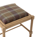 Angled close-up of the Hank Cocktail Table Ottoman highlighting the cushioned wool plaid seat. The upholstery features a warm mix of rust, blue, gold, and muted neutral tones.
