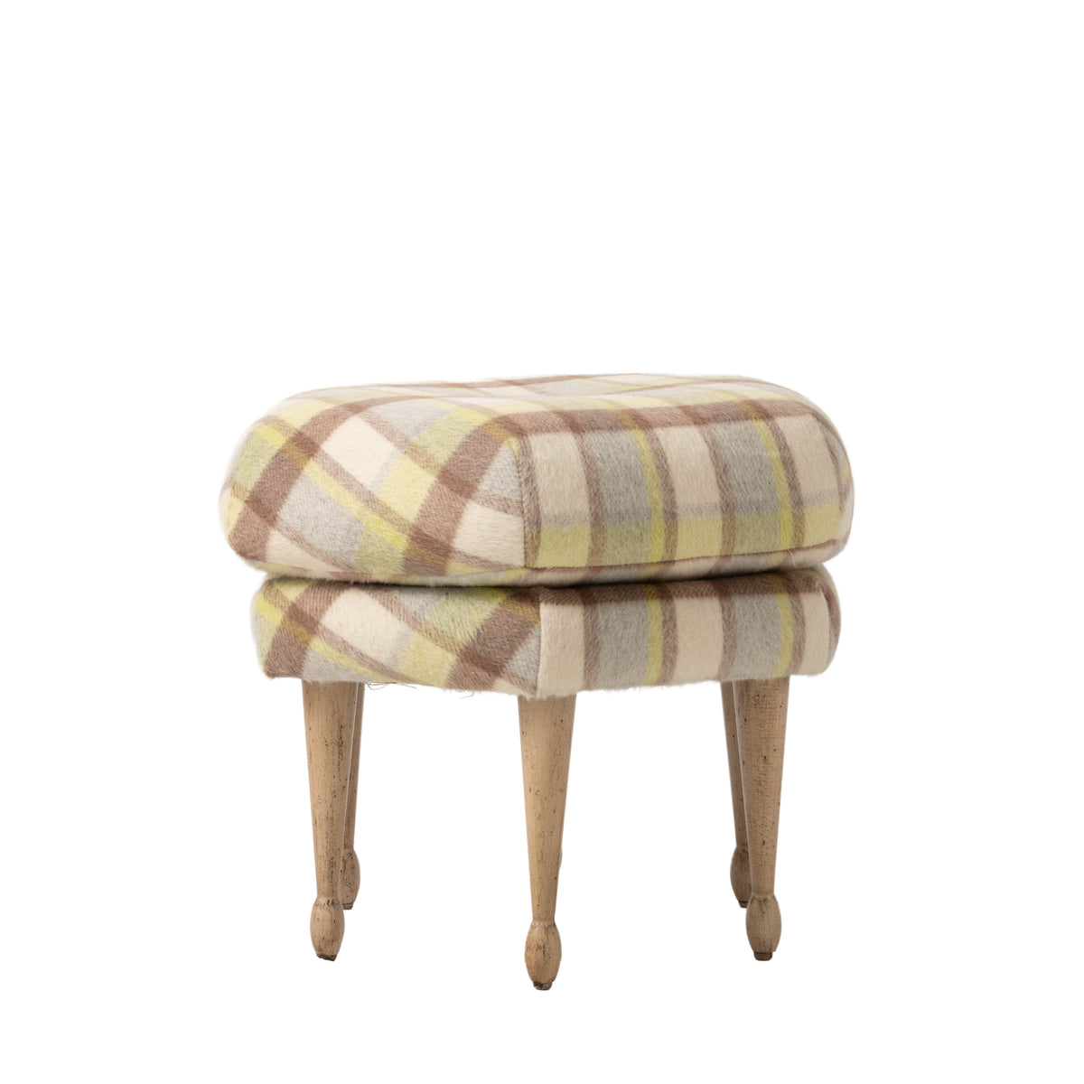 Three-quarter view of the plaid upholstered ottoman highlighting its rounded cushion, tailored base, and tapered wood legs. The soft cream, taupe, and green palette gives the piece a warm, understated look.