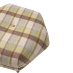 Close-up of the ottoman’s rounded cushion upholstered in a soft plaid fabric. Cream and taupe tones are accented with subtle pale green stripes for a classic, neutral pattern.
