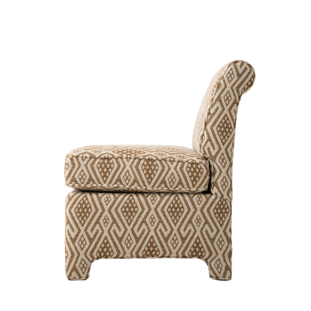 Side profile of the armless accent chair showing its gently angled back, thick seat cushion, and upholstered base. A neutral brown and cream geometric fabric covers the entire chair.