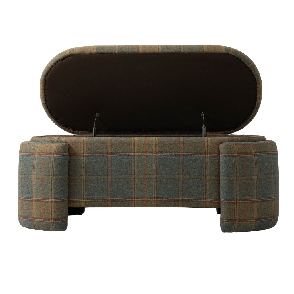 Front view of the upholstered plaid bench with its hinged seat lifted to reveal a hidden storage compartment. The bench features muted green, brown, and rust plaid upholstery with substantial rounded legs at each end.