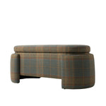 Three-quarter view of the upholstered bench featuring a thick cushioned seat and sculptural rounded legs. The bench is covered in a muted green and brown plaid fabric accented with fine rust-colored lines.