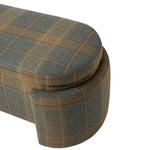 Close-up of the bench highlighting its rounded cushioned seat, curved upholstered leg, and tailored construction. The textured plaid fabric features muted green and blue tones with warm brown and rust accents.
