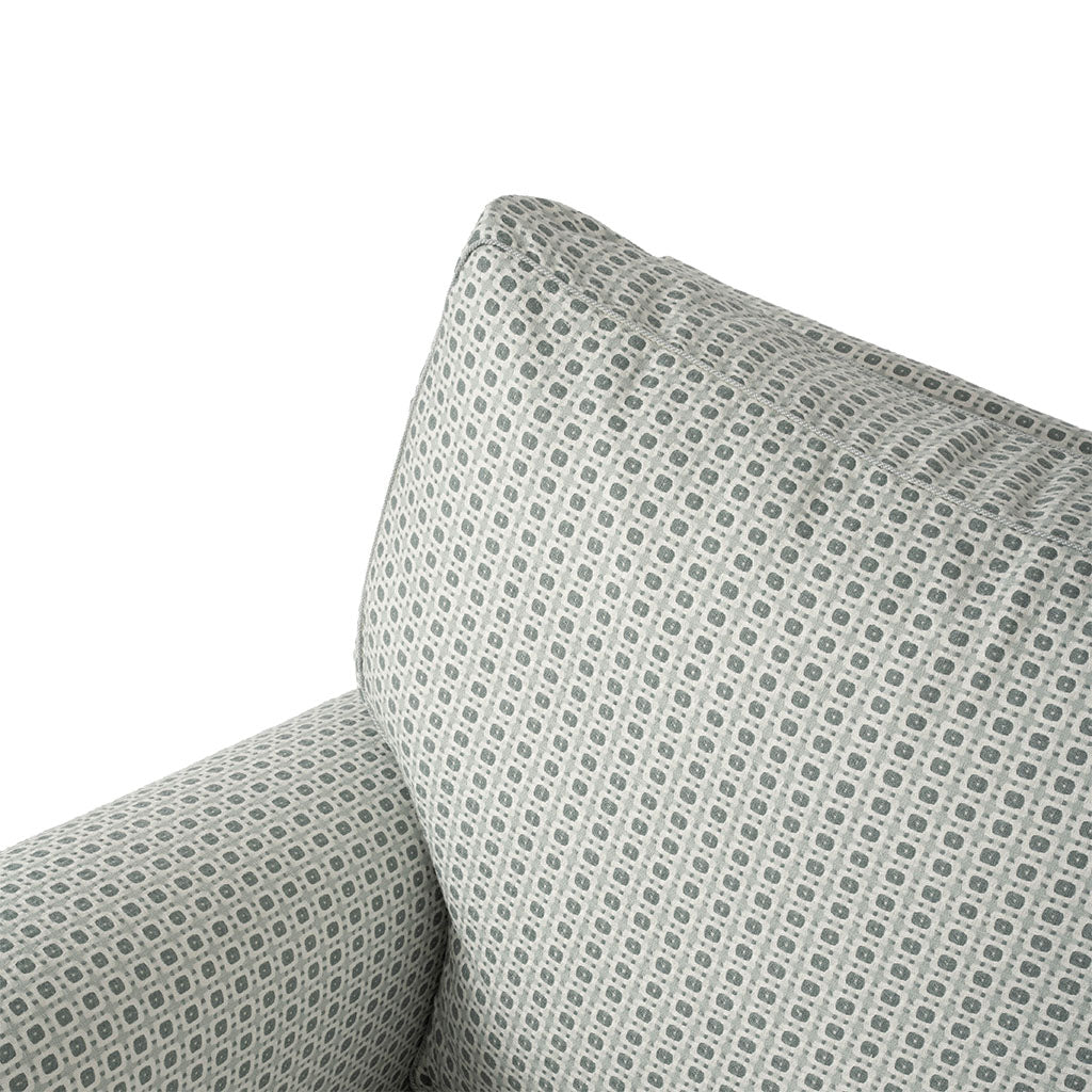 Close-up of the chair’s back and arm, highlighting the tailored upholstery and softly cushioned construction. The miniature geometric pattern continues seamlessly across the chair.