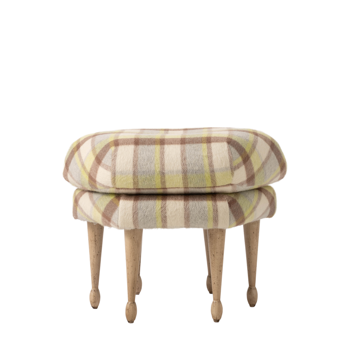 Upholstered ottoman featuring a softly rounded cushion in a cream, taupe, and pale green plaid fabric. Four tapered natural wood legs give the piece a light, elegant silhouette.