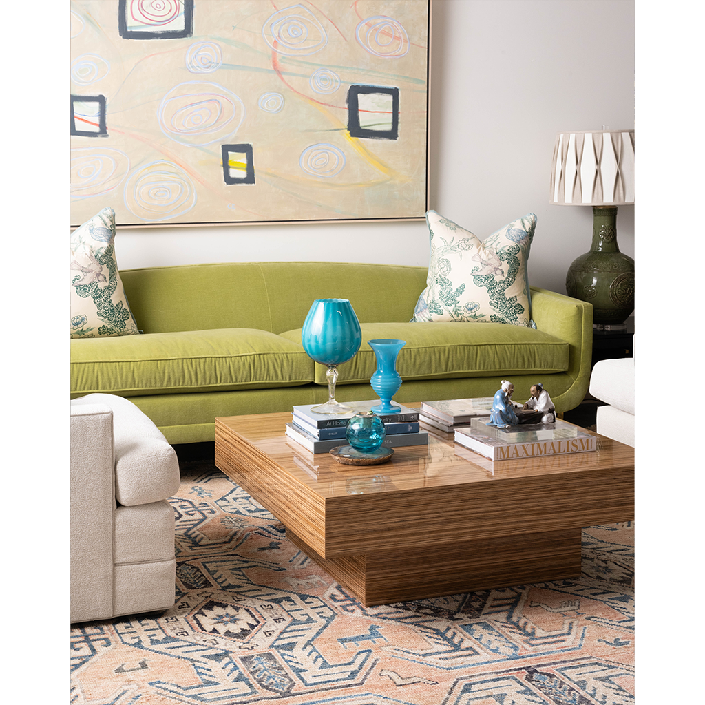 Interior with carter cocktail table in zebrawood, green velvet sofa with patterned pillows, and a coral and blue rug