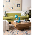 Interior with carter cocktail table in zebrawood, green velvet sofa with patterned pillows, and a coral and blue rug