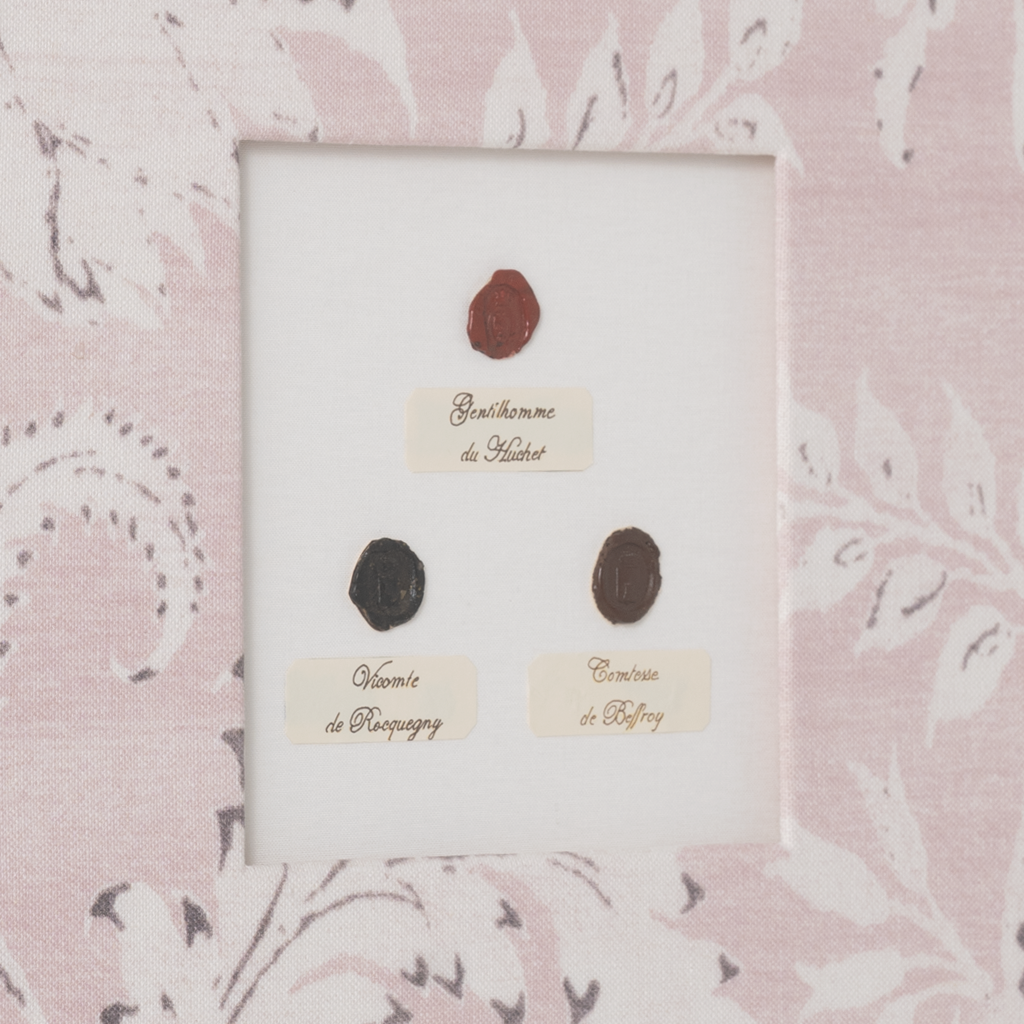 Three black oval stamps on a white card with text, set against a pink floral patterned background.