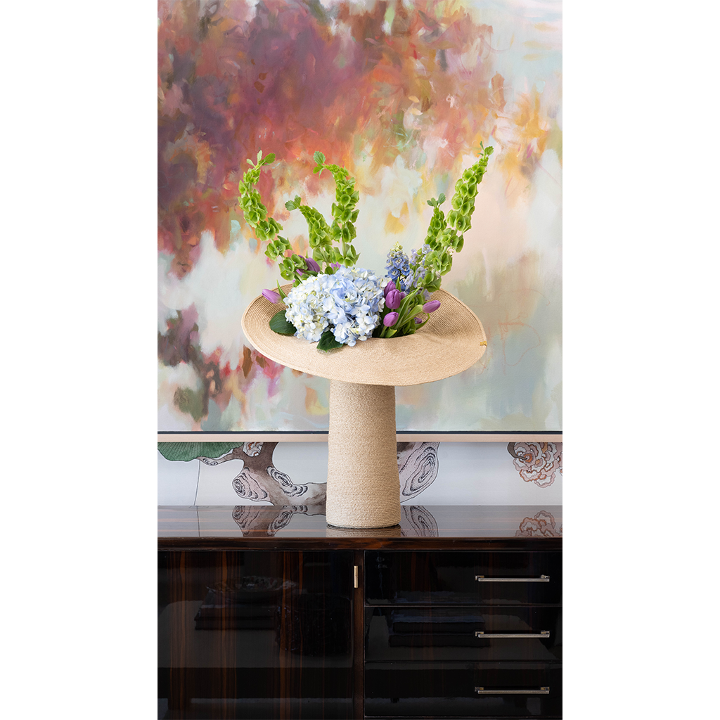 Raffia lapel vase on a console with abstract art and floral arrangment
