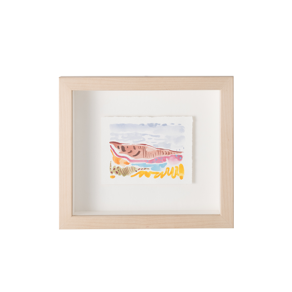 A framed art print featuring a colorful watercolor illustration of a fish on a white background, housed in a light natural wood frame with a white mat.