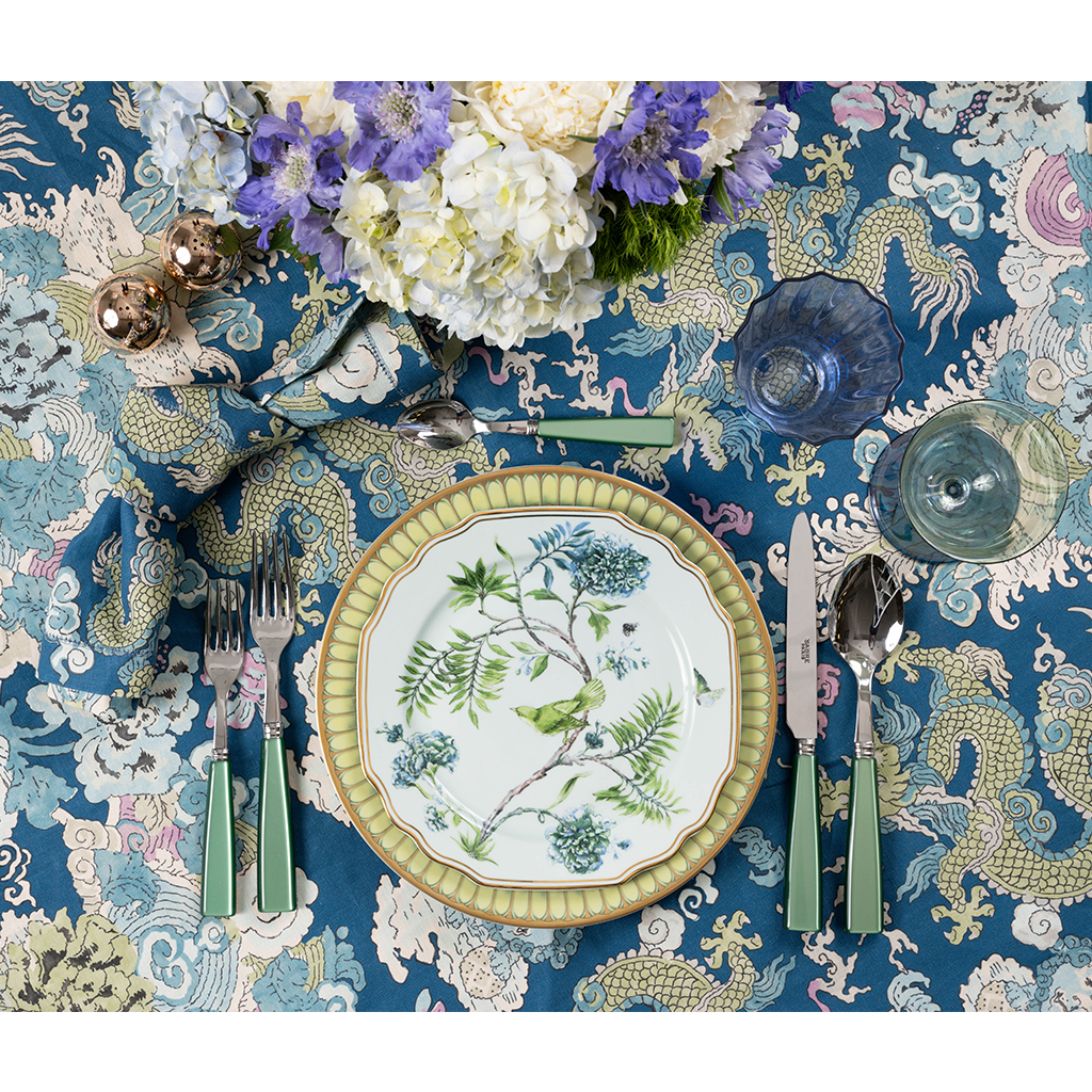 Blue and cream patterned Magic Mountain Napkin with intricate floral and dragon designs under a white plate with bird.