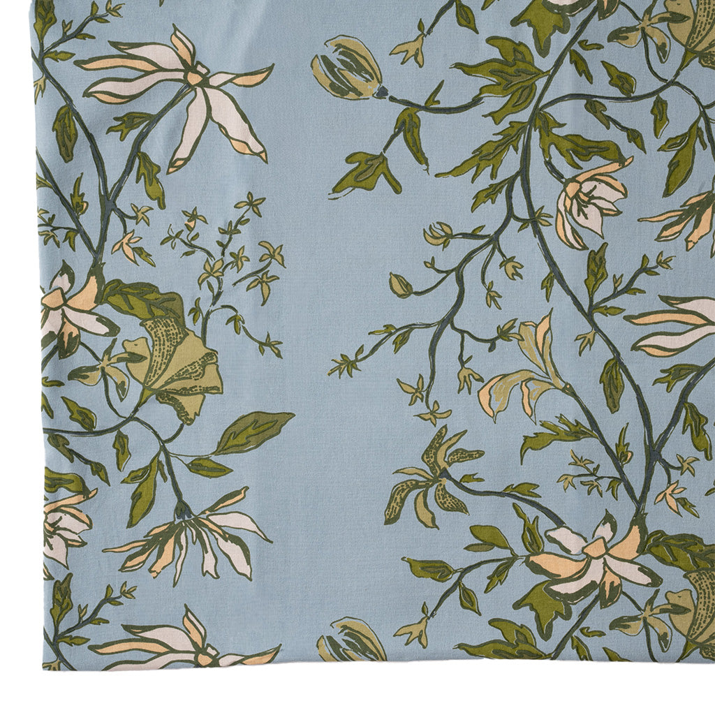 close up image of a blue and green botanical tablecloth on a white background
