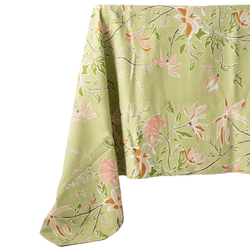 image of a green and orange botanical tablecloth draped off of a table on a white background