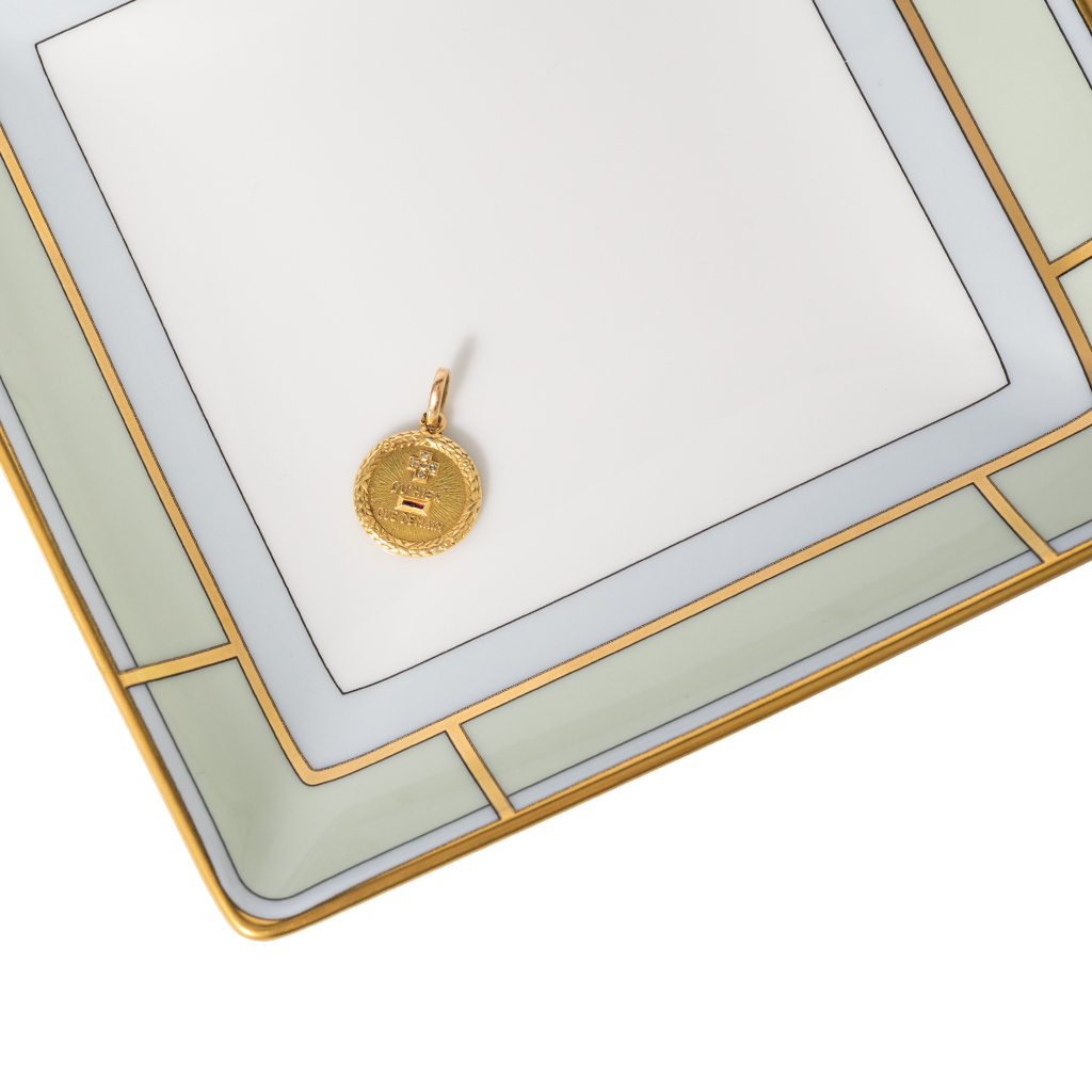 Gold pendant on a decorative white and gold frame
