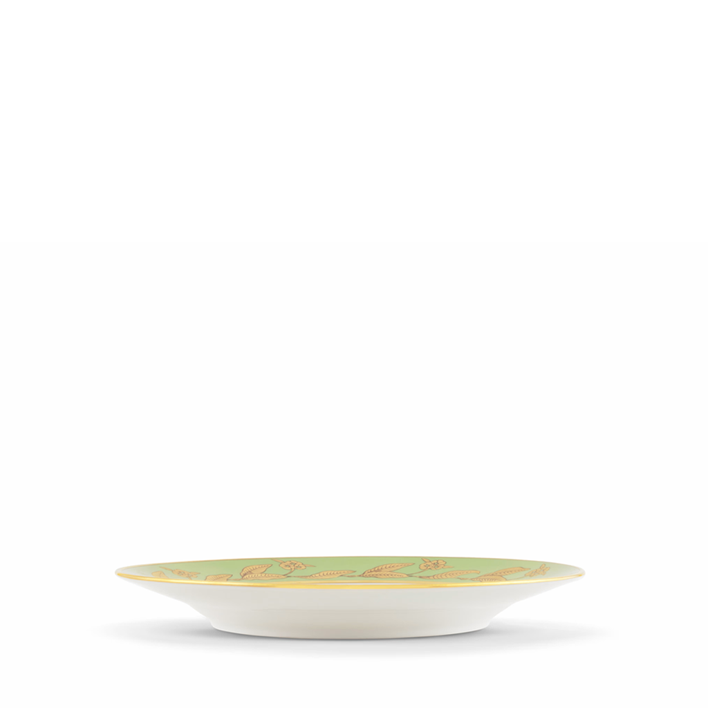 side view of green and gold dessert plate on a white background