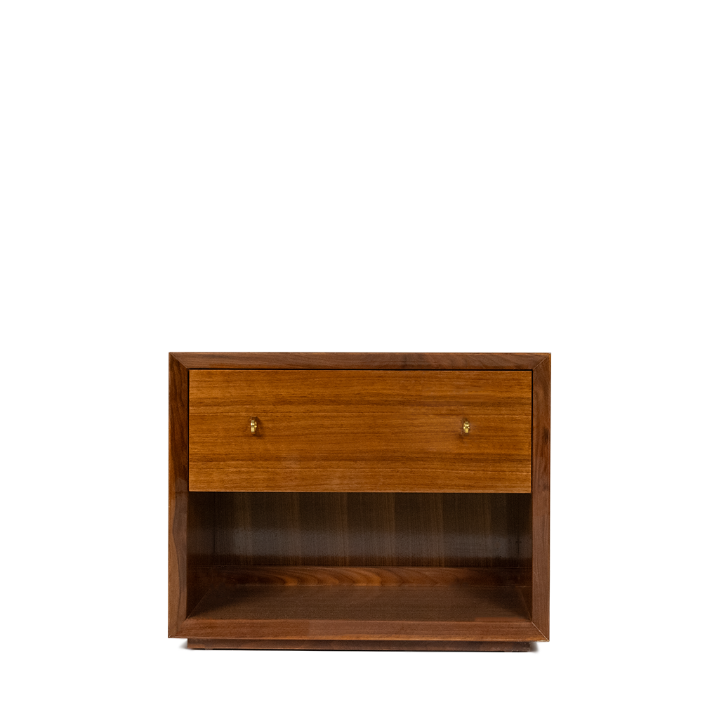 A walnut veneer side table with one shelf and one drawer, featuring brass hardware and a floating plinth base.