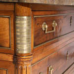 Close-up of a wooden dresser with brass handles and decorative elements.
