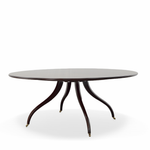Elegant oval dining table featuring a smooth, dark mahogany finish and a slim tabletop with a gently rounded edge. The sculptural pedestal base features four gracefully curved legs with delicate brass-capped feet, creating a timeless, sophisticated silhouette.