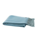 A folded light blue throw blanket with fringed edges, displayed on a clean white background.