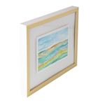 A framed abstract landscape art print with colorful wavy hills in shades of green, yellow, and blue, set in a light natural wood frame with a white mat on a white background.