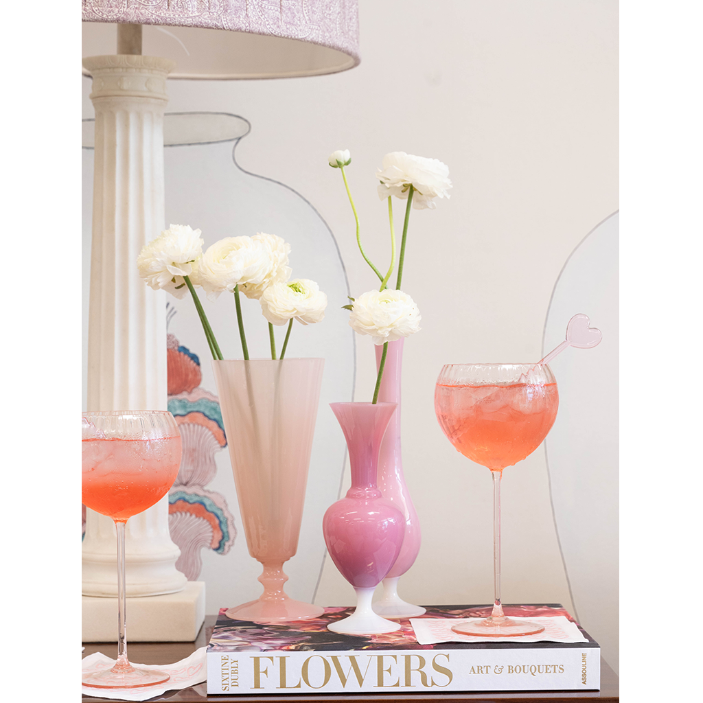 Pink hardcover book titled Flowers with white and pale yellow ranunculus in frosted pink and glossy purple vases and two.