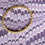 Decorative gold bangle on a purple and white patterned background