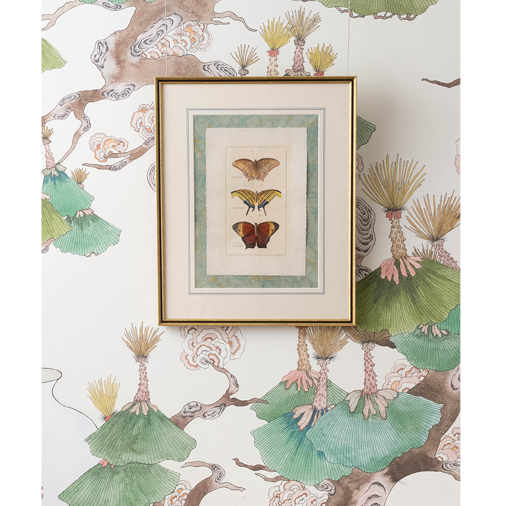 A framed art print featuring three vintage butterfly illustrations, displayed on a wall with a matching botanical patterned wallpaper.